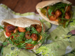 Tex Mex -siskonmakkara pitaleivät vihreällä liinalla, täytteenä rapeaksi paistettuja makkarapalleroita ja tuoreita kasviksia.