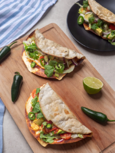 Siskonmakkara smashed tacos puisella leikkuulaudalla, täytteenä vihanneksia, avokadoa, jalapenoa ja korianteria.