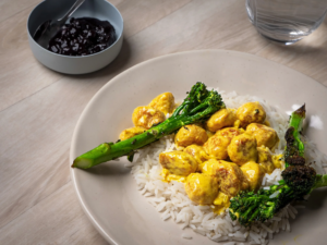 Curry-broiler siskonmakkarakastike Wurstin broilerisiskonmakkaroista, tarjoiltuna riisin ja paahdetun parsakaalin kanssa.