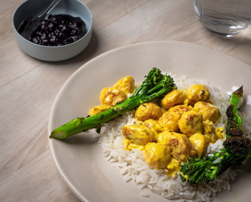 Curry-broiler siskonmakkarakastike Wurstin broilerisiskonmakkaroista, tarjoiltuna riisin ja paahdetun parsakaalin kanssa.