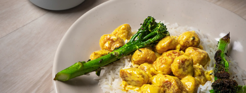 Curry-broiler siskonmakkarakastike Wurstin broilerisiskonmakkaroista, tarjoiltuna riisin ja paahdetun parsakaalin kanssa.